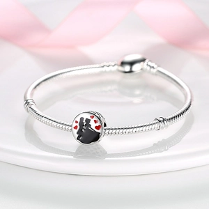 Close-up of silver snake chain bracelet featuring a romantic couple silhouette charm