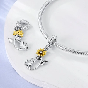 Detalle del dije de girasol y gato en plata S925 con circón en pulsera de serpiente