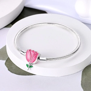 Dettaglio macro del charm tulipano in smalto rosa su un bracciale a catena serpente argento