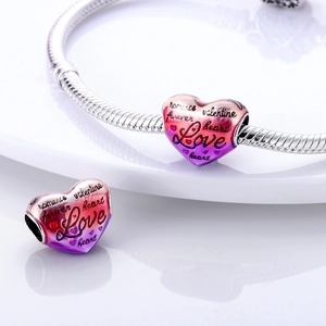 Macro detail of heart charm with Love and Romance engraving on silver snake chain