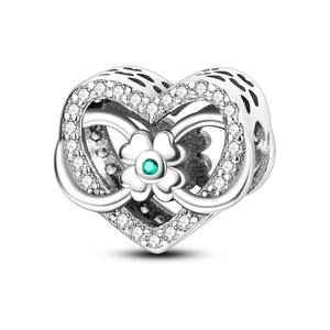 Macro shot of silver heart charm with green clover gemstone and sparkling zircons
