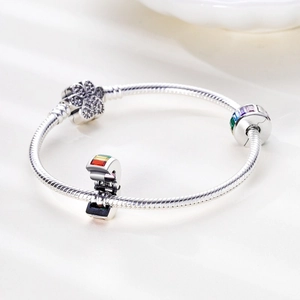 Silbernes Schlangenarmband mit Smaragdschliff-Anhängern und Zirkonen auf Seidenhintergrund