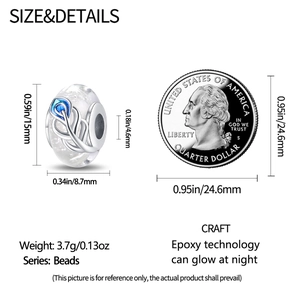 Luminous white glass charm with teal feather detail next to a US quarter coin