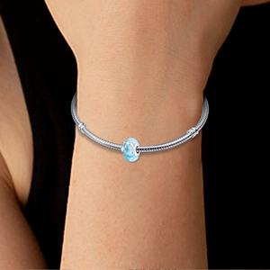 Detailansicht eines silbernen Schlangenarmbands mit blauem Delfin-Glasperlen-Anhänger