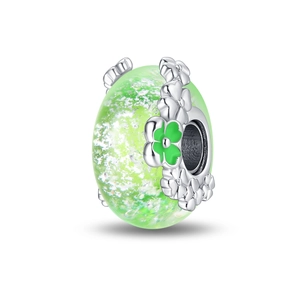Detailed view of luminous green glass bead with silver flower and four-leaf clover design