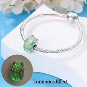 Detailed view of silver snake chain bracelet and luminous green flower bead charm