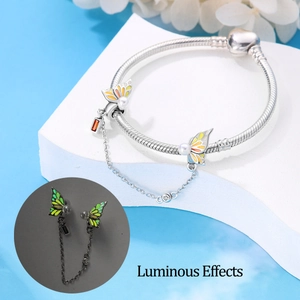 Detalle de dijes de mariposa luminosos y gema naranja en cadena de serpiente plateada