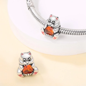 Detail of silver cat charm with orange heart gem on a snake chain bracelet