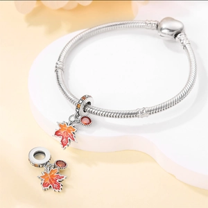 Macro shot of maple leaf charms on a silver snake chain bracelet with heart clasp