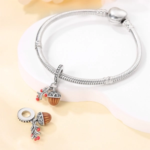 Detailed view of silver acorn and maple leaf charms on a sleek snake chain bracelet
