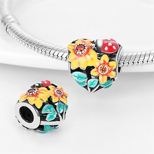 Macro detail of sunflower charm with yellow enamel petals and a small red ladybug