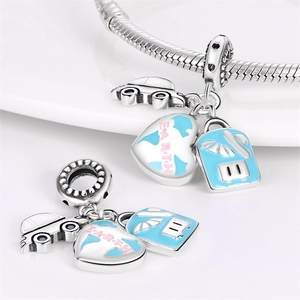 Macro shot of silver travel charms featuring a blue car, Earth map heart, and a suitcase