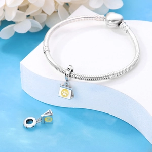 Detail of silver snake chain bracelet with yellow cat paw charm on white display