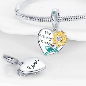 Macro shot of silver heart sunflower charm with You are my sunshine engraving and crystal