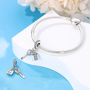 Detail view of heart-shaped lock and engraved key charm on a silver snake chain bracelet