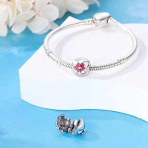 Détail du bracelet en maille serpent argentée avec breloque papillon rose et pierre orange