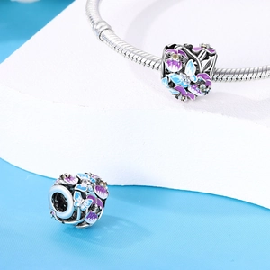 Détail d'un charm en argent avec émail papillon bleu-violet, fleurs et cristaux fins