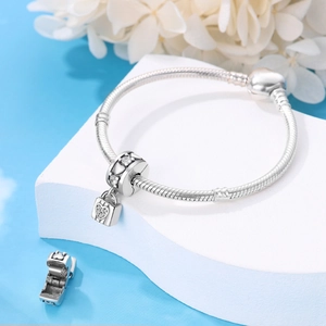Detailed view of a silver heart lock charm with sparkling stones on a snake chain bracelet