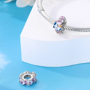 Détail de charms en émail argenté avec fleurs et papillon sur un bracelet chaîne serpent