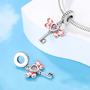 Macro shot of silver key charm with heart stone and wings for DIY bracelet