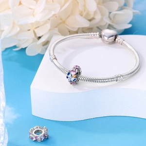 Gros plan détaillé des breloques émaillées papillon et fleur sur bracelet argenté