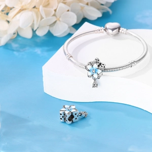 Gros plan sur bracelet maille serpent en argent avec breloques fleurs bleues et pendentif