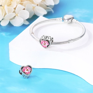 Détail de charms fleurs avec émail rose et cristaux sur bracelet maille serpent argenté