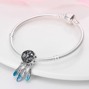 Makro-Detail des Traumfänger-Anhängers mit Zirkonia und Emaille-Federn an einem Armband
