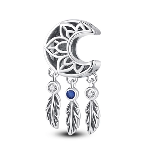 Detailed macro shot of a moon and lotus dreamcatcher charm with silver feathers and blue stones