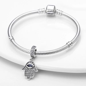 Detalle de pulsera de cadena de plata con colgante mano de Fátima y piedra de circón azul