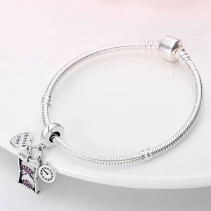 Detailansicht eines silbernen Schlangenarmbands mit Herz-, Uhr- und Sanduhranfängern