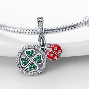 Vue macro du pendentif trèfle avec pierres vertes et coccinelle sur chaîne en argent