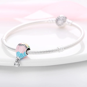 Detailaufnahme des silbernen Schlangenarmbands mit einem bunten Heißluftballon Anhänger
