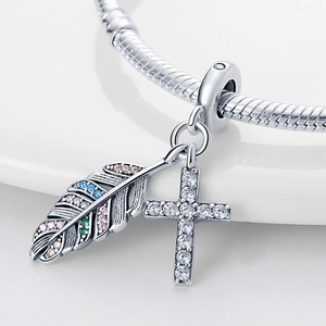 Détail d'un pendentif en argent en forme de plume et croix avec des zircons colorés