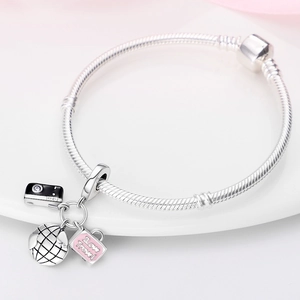 Detailansicht von Reise-Anhängern mit rosa Koffer und silbernem Globus auf Armband