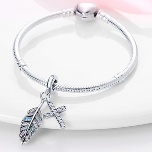 Détail macro d'un bracelet maille serpent en argent avec pendentifs plume et croix