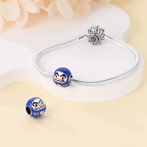 Dettaglio del bracciale a maglia snake con ciondoli Daruma in smalto blu portafortuna