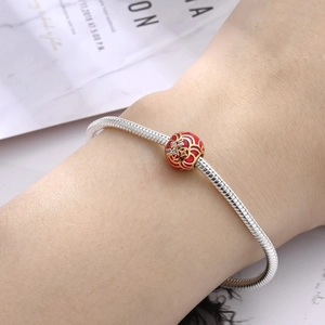 Dettaglio charm leone in smalto rosso su bracciale a catena snake argento