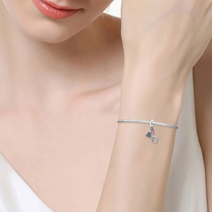 Detail eines silbernen Badminton-Armbands mit rosa Emaille am Handgelenk einer Frau