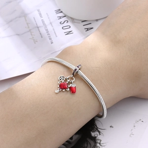Dettaglio del bracciale a maglia serpente argento con ciondoli portafortuna in smalto rosso