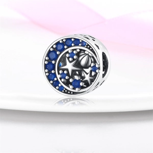 Primer plano de un abalorio de plata con piedras azules y diseño de luna creciente y estrellas