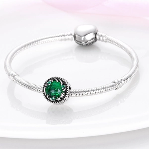Vista detallada de pulsera de cadena de plata con dije de cristal verde y cierre de corazón