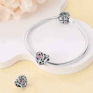 Detail of silver snake chain bracelet with hollow heart charms and pink zircon