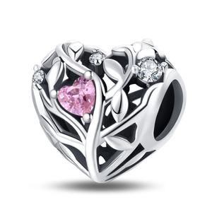 Macro view of heart-shaped hollow charm with pink zircon and intricate vine patterns