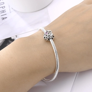 Detailed close-up of a silver snake chain bracelet featuring pink gemstone heart charms