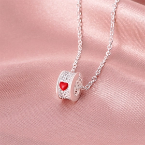 Close-up of silver cylinder pendant with heart enamel and micro-paved zircons on pink silk