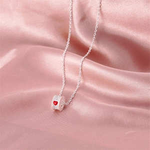 Close-up of silver cylinder pendant with white pavé stones and a red heart center