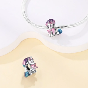 Macro shot of silver unicorn charm with purple gradient enamel on snake chain bracelet