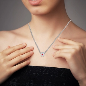 Close-up of a silver cylinder pendant with pavé diamonds and a red heart on a necklace