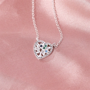 Macro detail of silver heart necklace with tree of life design and colorful gemstones